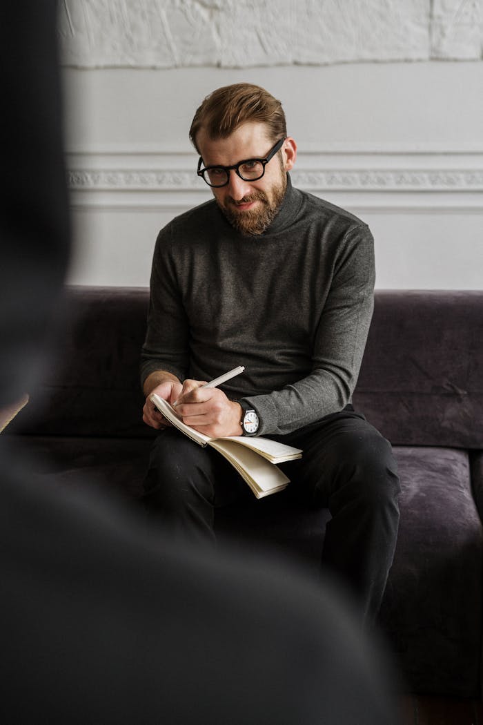 ROSARIUM CONSULTING Male professional in a cozy office setting taking notes during a session or meeting.